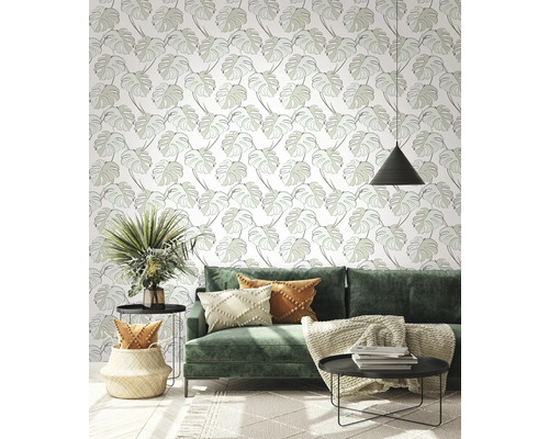 Wohnzimmer mit grüner Couch, Beistelltischen und Tapete mit Blattmuster