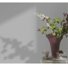 Dekoratives Stillleben mit Blumen in einer Vase, Tasse und Gebäck auf einem Tisch