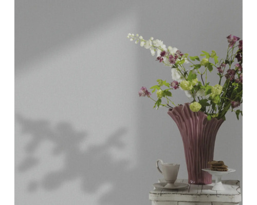 Dekoratives Stillleben mit Blumen in einer Vase, Tasse und Gebäck auf einem Tisch