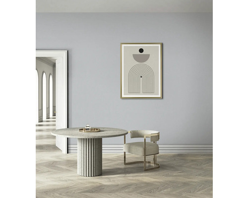 Helles Interieur mit einem runden Esstisch, einem Stuhl und einem gerahmten Kunstdruck an der Wand
