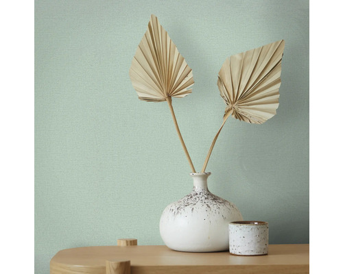 Detailansicht einer Wand mit einer hellen Vliestapete und dekorativen Elementen.