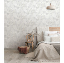 Ein Schlafzimmer mit einer Wand, die mit einer Tapete mit Pflanzenmuster verziert ist, einem Bett und einem Stuhl.