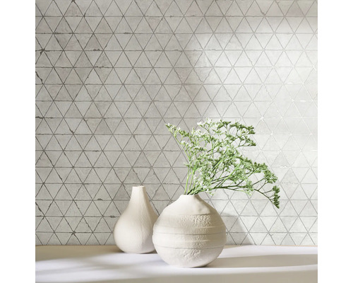 Dekorative Wandfliesen mit Dreiecksmuster und zwei Vasen auf einem Regal.