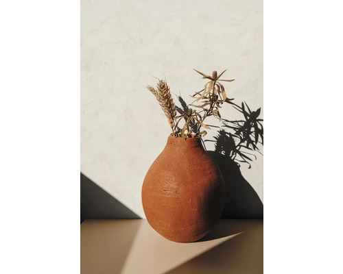 Dekorative Tonvase mit Trockenblumen auf einem Tisch