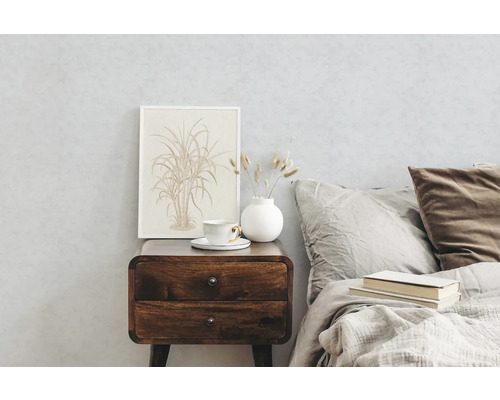 Schlafzimmer mit Nachttisch aus Holz, Tasse, Vase und gerahmtem Bild