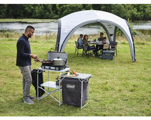 Szene mit Campingküche, Koch und Pavillon auf einer Wiese