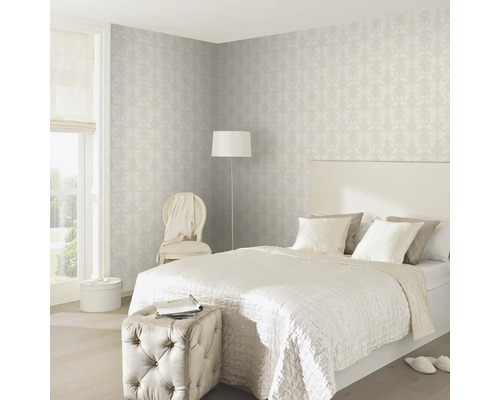 Schlafzimmer mit Bett, Sessel, Stehlampe und gemusterter Tapete