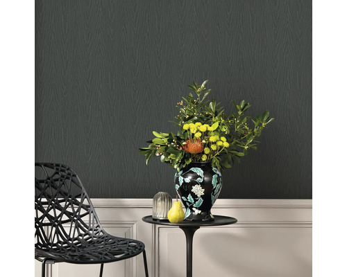 Dekoratives Wohnzimmer mit schwarzer Design Tapete in Holzoptik, einem Beistelltisch mit Blumenvase und einem Design Stuhl.