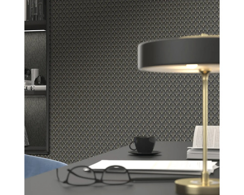 Nahaufnahme einer Wand mit Tapete im Art-déco-Stil, ergänzt durch einen Schreibtisch mit Lampe, Brille, Kaffeetasse und Büchern.