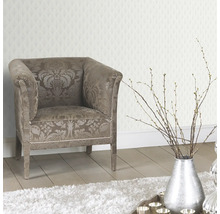 Dekoratives Interieur mit Sessel, silberfarbener Vase und gemusterter Tapete
