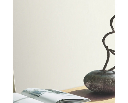 Helle Wand mit Vase, Ästen und Buch auf einem Tisch.