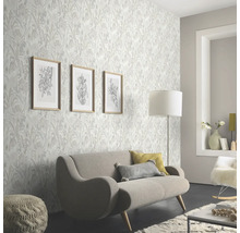 Wohnzimmer mit floral gemusterter Tapete, Sofa und Dekorationen für eine helle und freundliche Atmosphäre.