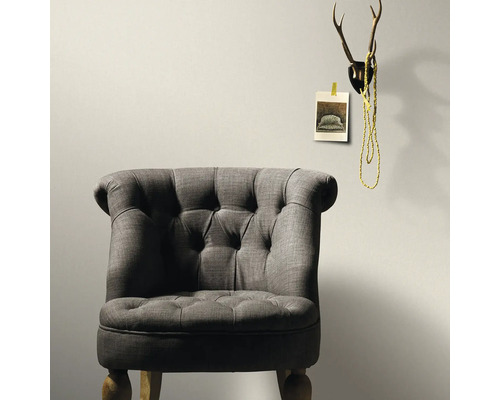 Grauer Sessel mit Knöpfen und Hirschgeweih als Wanddekoration