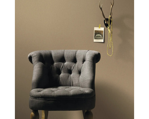 Grauer Sessel mit Knopfleiste vor einer Wand