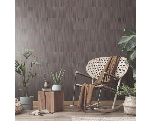 Wohnraum mit gemusterter Tapete, Schaukelstuhl, Beistelltisch und Pflanzen.
