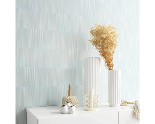 Wohnraum mit gemusterter Wand und Dekorationsgegenständen auf einem weißen Schrank