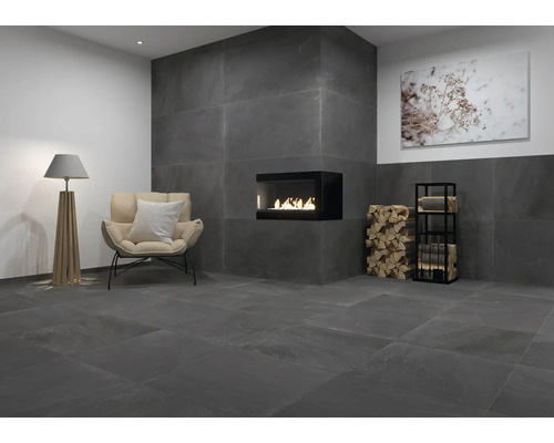 Wohnzimmer mit anthrazitfarbenen Fliesen, Kamin, Sessel und Stehlampe