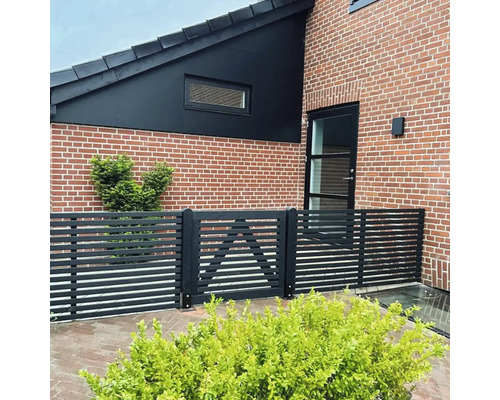 Außenansicht eines Hauses mit Backsteinfassade und einem Holzzaun mit Tor