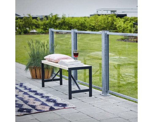 Bank mit Metallgestell, Kissen, Büchern und Weinglas auf einer Terrasse