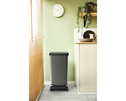 Grauer Treteimer im Küchenbereich vor einem Küchenschrank und einer Jalousie