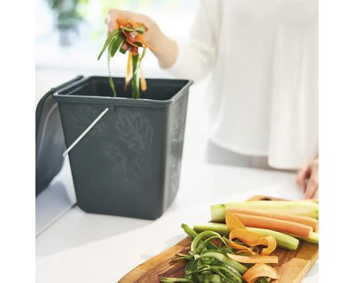 Komposteimer mit Gemüseabfällen und Person