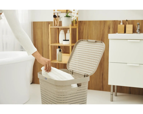 Person legt Wäsche in einen Wäschekorb im Badezimmer