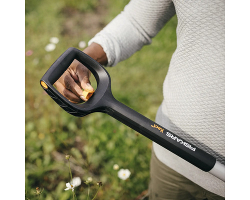 Nahaufnahme einer Person, die einen Spaten von Fiskars hält, um im Garten zu arbeiten.