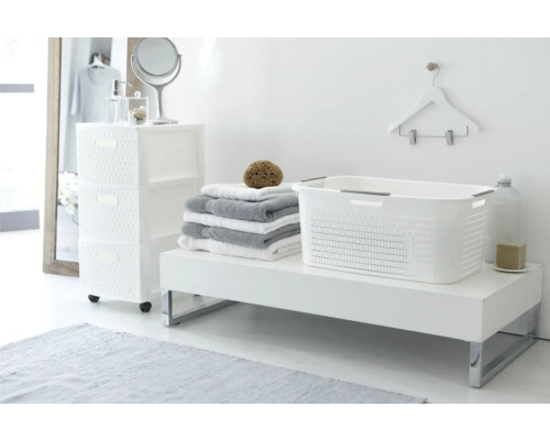 Badezimmerinterieur mit weißem Kunststoffwäschekorb, Handtüchern und Kommode