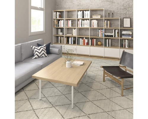 Wohnzimmer mit Sofa, Couchtisch, Regal und Sessel auf einem gemusterten Teppich