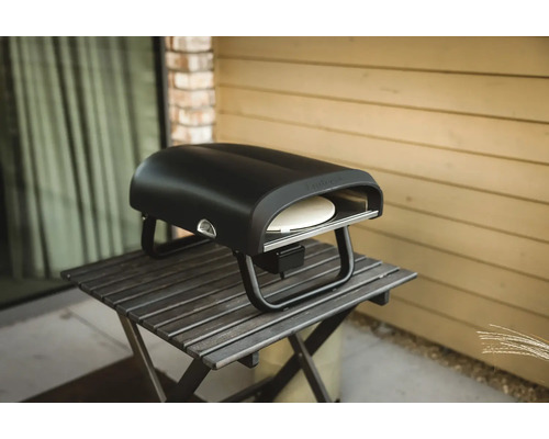 Schwarzer Pizzaofen auf einem Tisch im Freien.