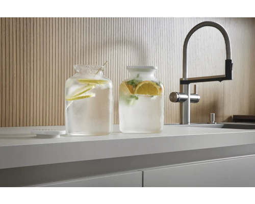 Zwei Glasbehälter mit Zitrusfrüchten und Wasser auf einer Küchentheke neben einem Wasserhahn