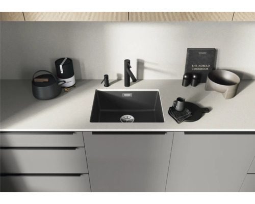 Küchenspüle mit Wasserhahn und Küchenutensilien auf einer Arbeitsplatte