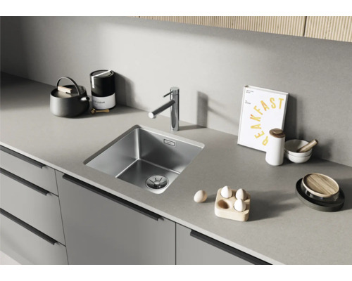 Küchenspüle aus Edelstahl mit Wasserhahn auf einer Arbeitsplatte.