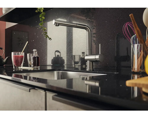 Küchenszene mit Spüle und Armatur auf einer dunklen Arbeitsplatte.