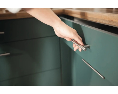 Detailaufnahme einer Hand, die einen Küchenschrank mit silbernem Griff öffnet.