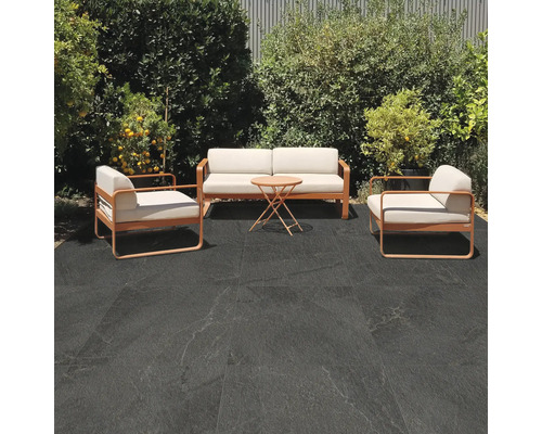 Terrasse mit Sitzgruppe und dunklen Bodenfliesen im Außenbereich.