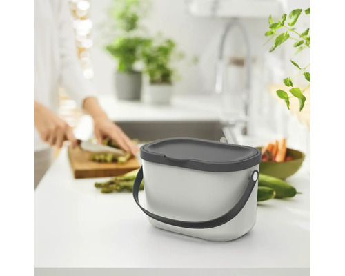 Komposteimer in einer Küche mit Person, die Gemüse schneidet