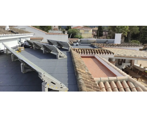 Installation von Solarmodulen auf einem Dach mit Ziegeln und Bitumenabdichtung.