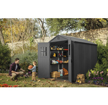Gartenszene mit einem Gerätehaus aus Kunststoff mit geöffneten Türen, Regalen und Lagergegenständen, ein Mann und ein Kind spielen mit einem Ball