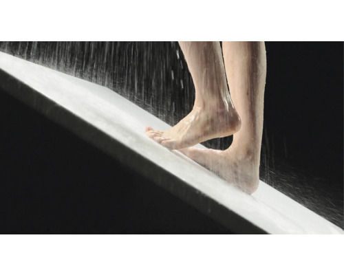 Person steht unter der Dusche in einer Duschwanne.