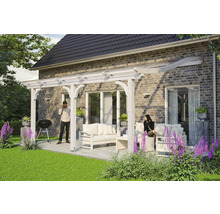 Terrasse mit Holzpergola und Sitzgruppe auf einer gepflasterten Fläche neben einem Haus.