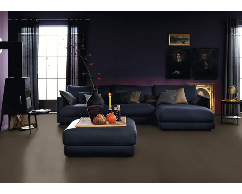 Wohnzimmer mit Sofa, Hocker, Kaminofen und dunklem Bodenbelag