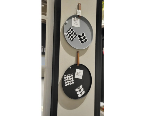 Zwei runde Memoboards in Grau und Schwarz mit Lederaufhängung an einer Wand.