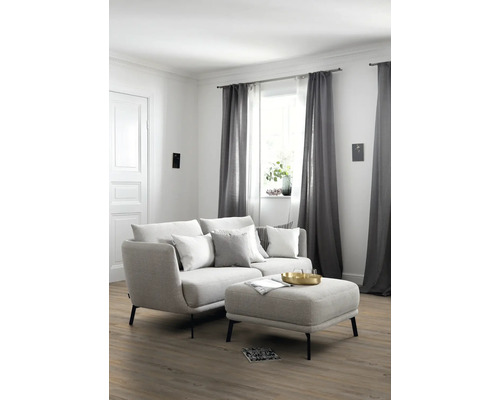 Helles Wohnzimmer mit Sofa, Ottomanen, Vorhängen und Holzboden