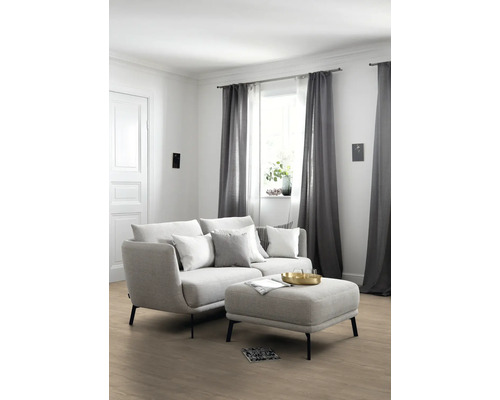 Wohnzimmer mit Sofa, Kissen, Hocker und Vorhängen für ein gemütliches Ambiente