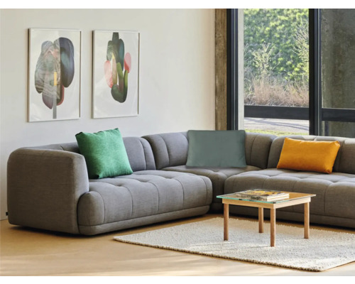 Wohnzimmer mit grauer Eckcouch, Kissen, Couchtisch und Wandbildern