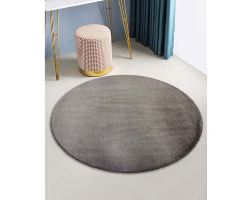 Grauer runder Teppich in einem Raum mit Hocker und Tisch
