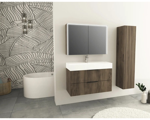 Badezimmer mit Waschtisch, Spiegelschrank, Hochschrank und Badewanne vor einer gemusterten Tapete