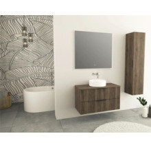 Badezimmer mit Waschtisch, Spiegel, Hochschrank und Badewanne vor einer Wand mit Blattmuster
