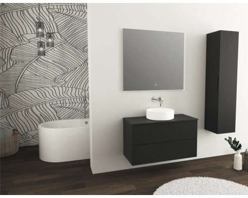 Modernes Badezimmer mit Waschtisch, Spiegel, Hochschrank und Badewanne vor einer Wand mit Blattmuster.